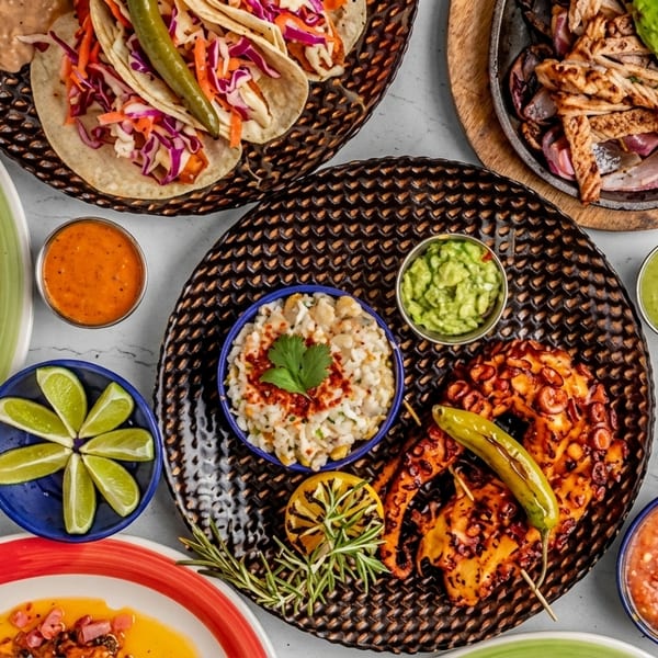 Overhead view of a vibrant Mexican food spread with tacos, quesadillas, grilled octopus, and various sauces.