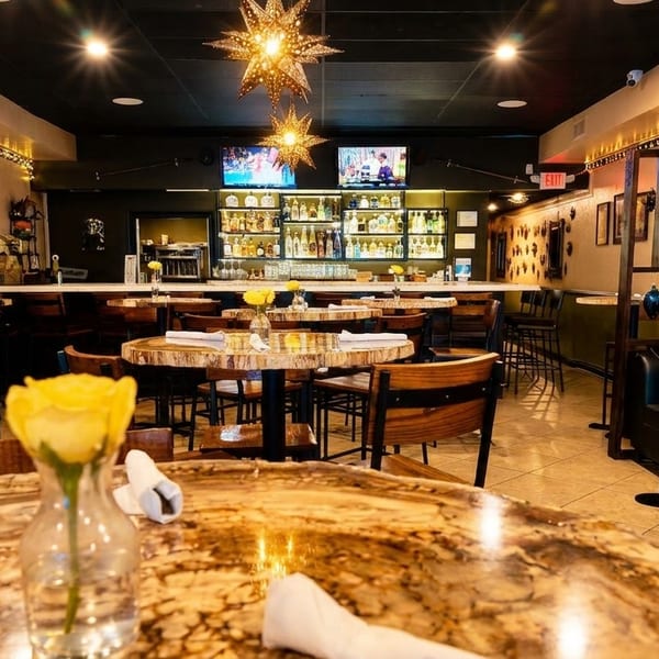 A vibrant restaurant interior with wooden tables, star-shaped lights, a full bar, and decorative wall accents.